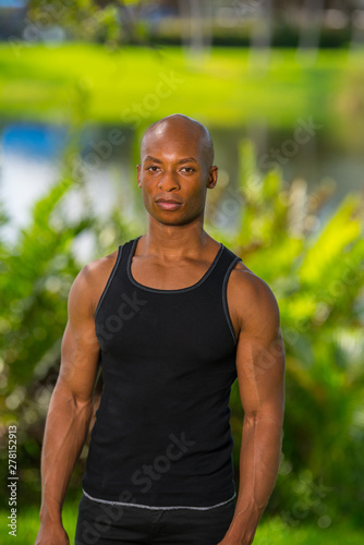 Portrait of a muscular fitness model posing in the park. Image lit with off camera flash