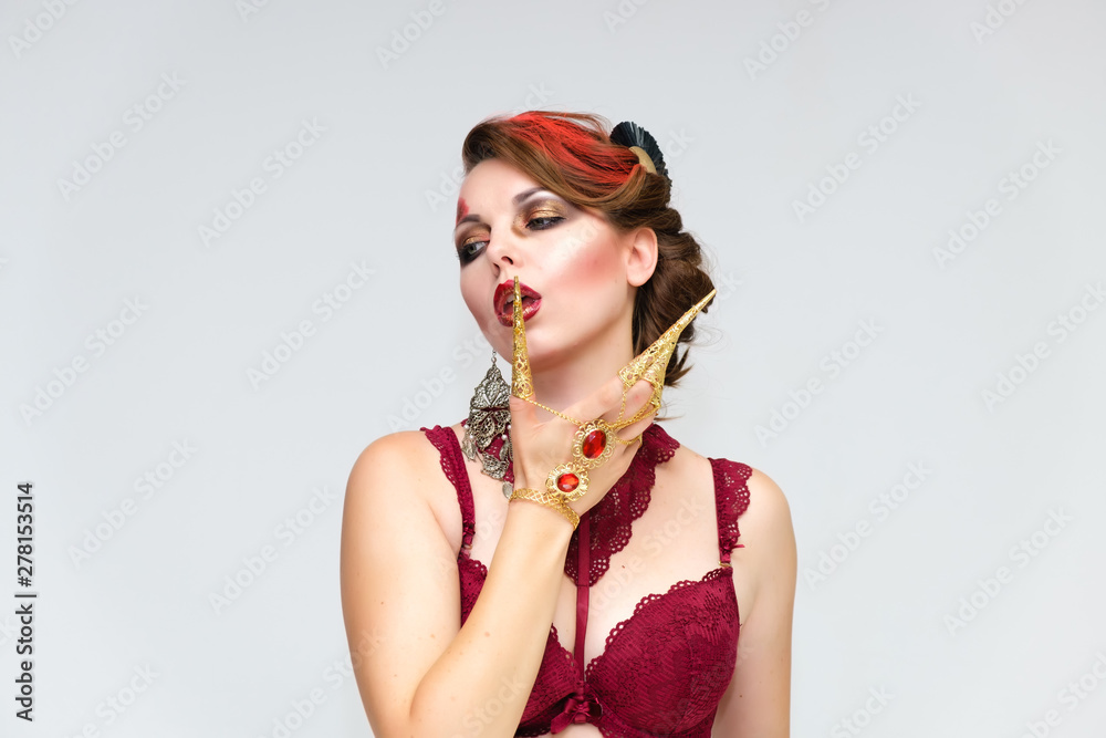 Naklejka premium Portrait to the waist on a white background of a pretty young brunette woman with beautiful makeup, with gold jewelry on her hand. Beauty, great makeup. Shows emotions.