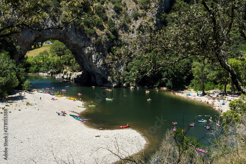 Top view of the Ardeche river near the famous Vallon Pont d'Arc arche with tourists kayaking, swimming et sun bathing. France.