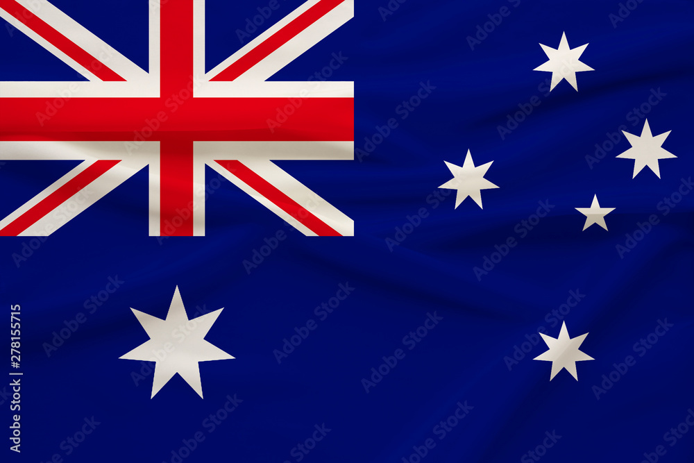 Fototapeta premium The national flag of the country of Australia on gentle silk with folds from the wind, the concept of travel, immigration, politics, copy space, close-up