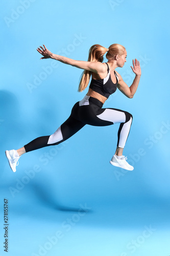 motivated woman runner on blue background. Dynamic movement. motivation. lifestyle, free time, spare time. studio shot. side view full length photo. cross fit