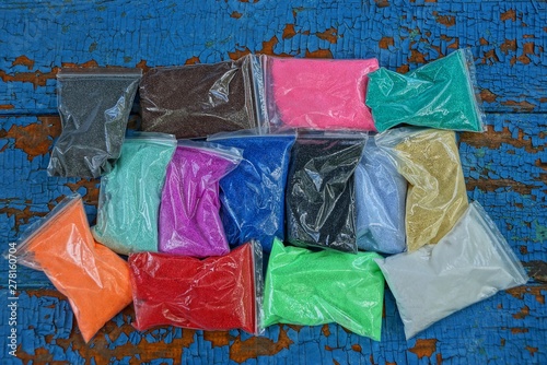 plastic bags with colored sand on a blue table