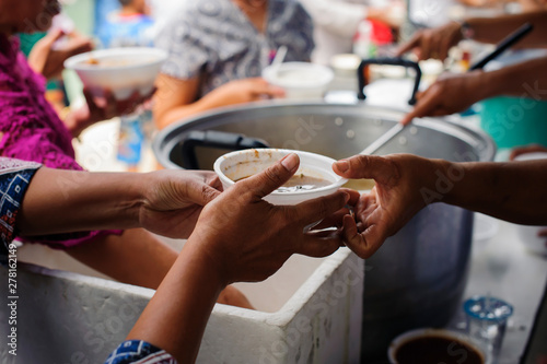 Concept of food sharing for the poor to alleviate hunger : Hands of beggars accepting food from the hands of volunteers who come to help free food breaks