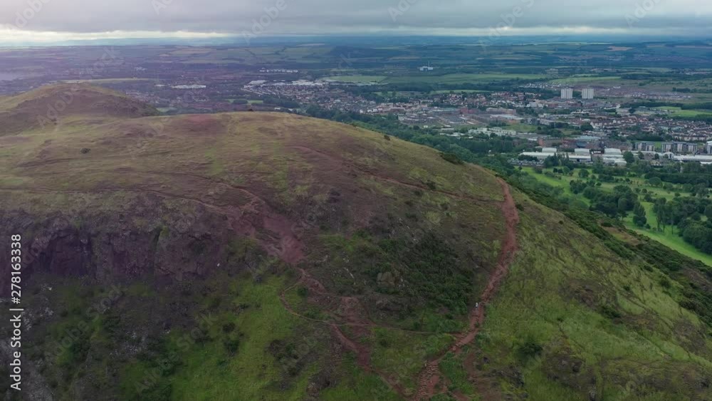 Aerial view of Edinburgh, capital city of Scotland, green hills and cliffs of Salisbury Crags in Holyrood Park - landscape panorama of Great Britain from above, United Kingdom, Europe Aerial view of Edinburgh, capital city of Scotland, green hills and cliffs of Salisbury Crags in Holyrood Park - landscape panorama of Great Britain from above, United Kingdom, Europe