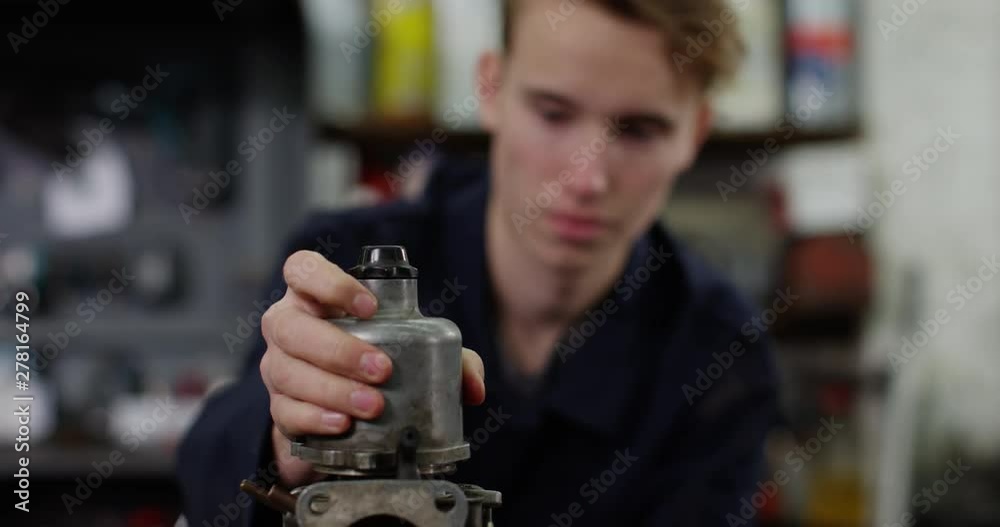 4K Confused trainee mechanic examining vehicle parts in auto repairs shop