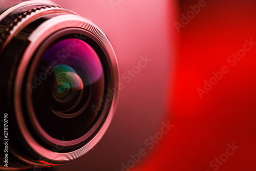 Camera lens with red backlight. Side view of the lens of camera on red background. Red  camera Lens close Up. Pure red photo