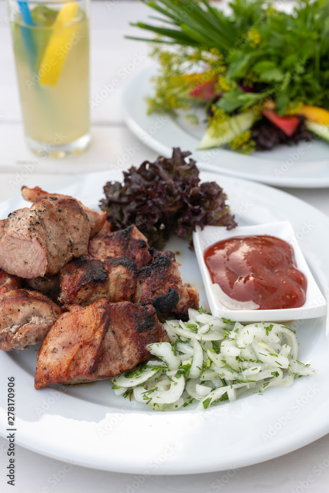 pieces of kebab with ketchup and onions on a plate pieces of kebab with ketchup and onions on a plate