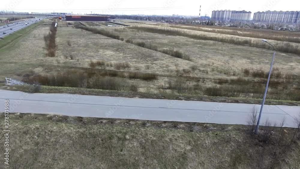 Beautiful aerial drone view of wide grey roads, fast moving cars, empty fields, rooftops, traffic and distant buildings in the densely populated urban area of large modern city on cloudy day. Beautiful aerial drone view of wide grey roads, fast moving cars, empty fields, rooftops, traffic and distant buildings in the densely populated urban area of large modern city on cloudy day.