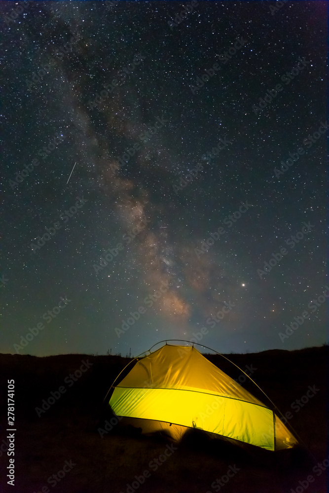 lightened touristic tent under a milky way, night travel landscape