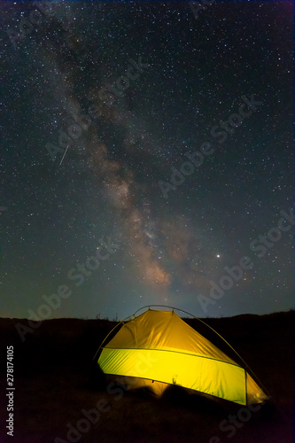 lightened touristic tent under a milky way, night travel landscape