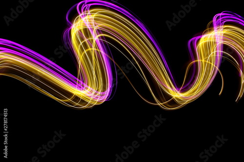 Long exposure light painting photography, curvy lines of vibrant neon pink and metallic yellow gold against a black background photo