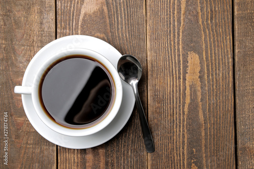 Coffee in a white cup and spoon on a brown wooden table. top view. space for text