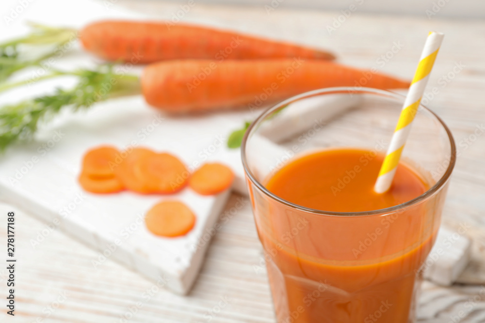 Glass of fresh carrot juice on white wooden table, space for text Glass of fresh carrot juice on white wooden table, space for text