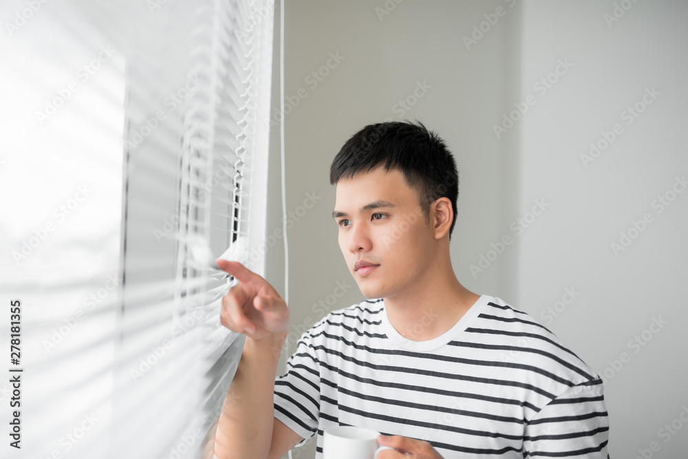 Young handsome carefree man near modern full length window enjoying a cup of coffee while looking outside, good morning, Young handsome carefree man near modern full length window enjoying a cup of coffee while looking outside, good morning,