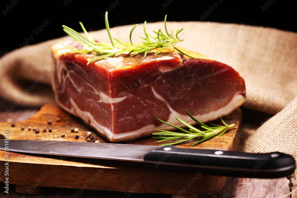 Italian prosciutto crudo or jamon with rosemary. Raw ham on wooden board Italian prosciutto crudo or jamon with rosemary. Raw ham on wooden board