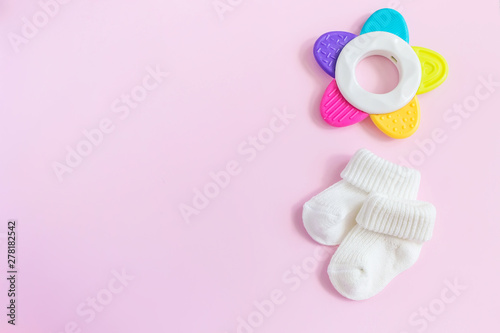 Baby accessories for newborns: socks and toy on pink background. Motherhood concept. Top view, flat lay composition.