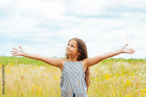 Emotional portrait of a little girl in the field enjoying the summer