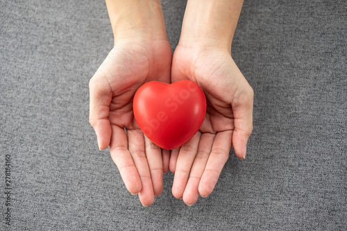 Woman holding and giving red heart in her hands.