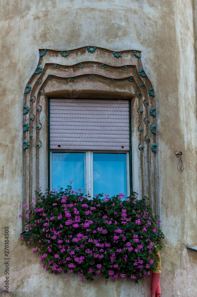 Little pink flowers decorating a window. Building facade.