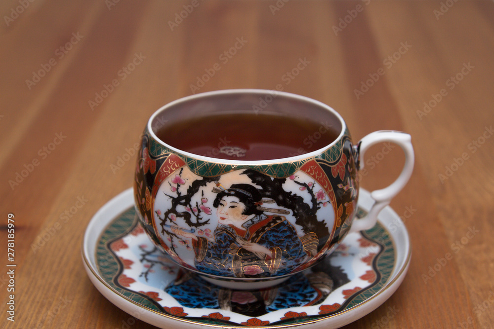 Fototapeta premium Chinese Cup with tea on a saucer. On a wooden table.