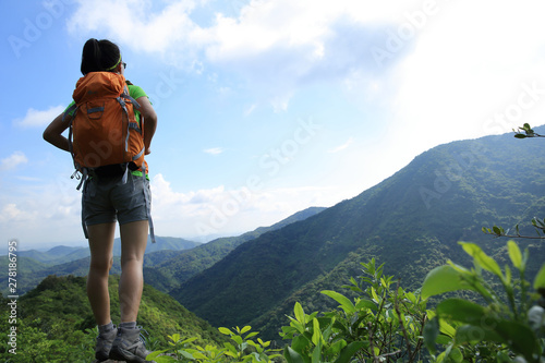 Young woman backpacker enjoy the view at summer mountain peak