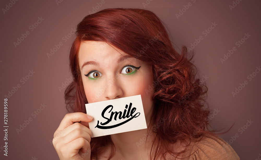 Person holding card with smile in front of her mouth Person holding card with smile in front of her mouth