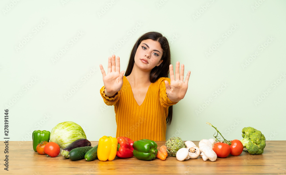 Teenager girl with many vegetables making stop gesture and disappointed Teenager girl with many vegetables making stop gesture and disappointed