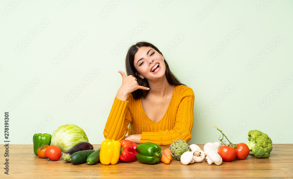 Teenager girl with many vegetables making phone gesture. Call me back sign Teenager girl with many vegetables making phone gesture. Call me back sign