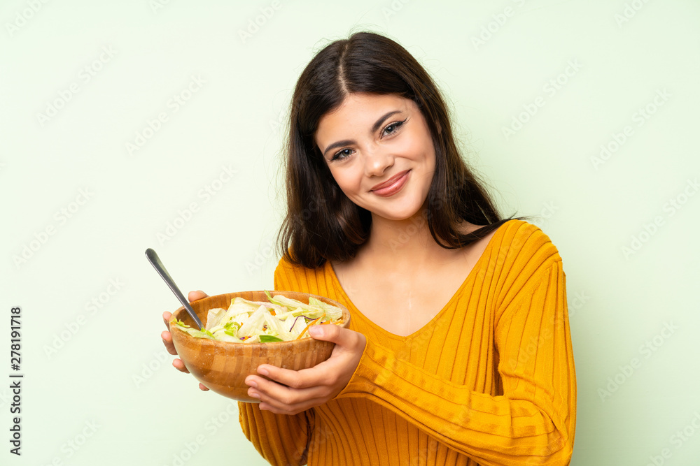 Happy Teenager girl with salad over green wall Happy Teenager girl with salad over green wall