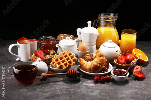 Huge healthy breakfast on table with coffee, orange juice, fruits, waffles and croissants. Good morning concept.