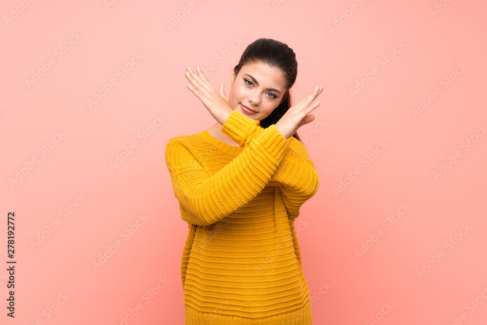 Teenager girl over isolated pink wall making NO gesture Teenager girl over isolated pink wall making NO gesture