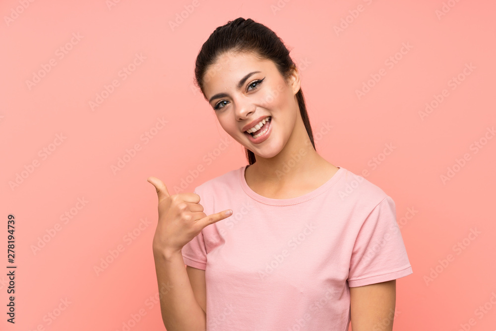 Teenager girl over isolated pink background making phone gesture Teenager girl over isolated pink background making phone gesture