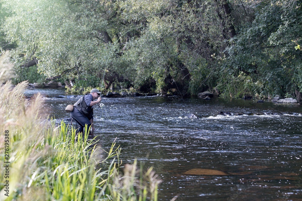 fisherman standing in the river and fly fishing fisherman standing in the river and fly fishing