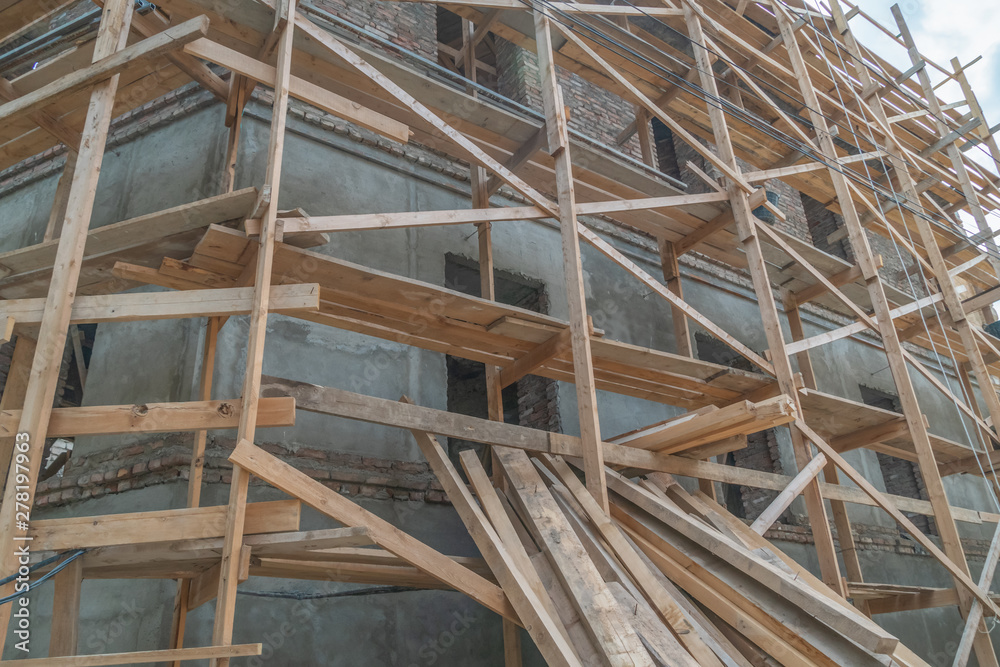 Home construction. Wooden scaffolding on a building close up Home construction. Wooden scaffolding on a building close up