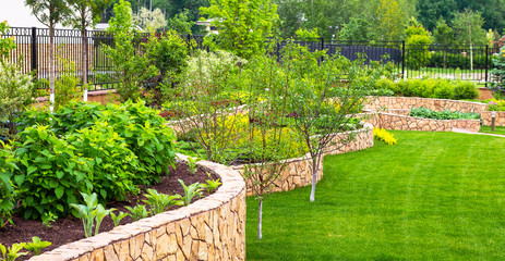Acrylglasbilder Pistache Landscaping in home garden. Beautiful natural landscape design with flower beds in summer. Panoramic view of landscaped part with plants in yard or backyard of residential house.  © scaliger