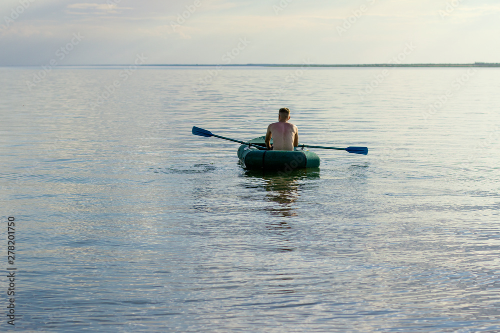 young man sailing on a lake in a boat young man sailing on a lake in a boat