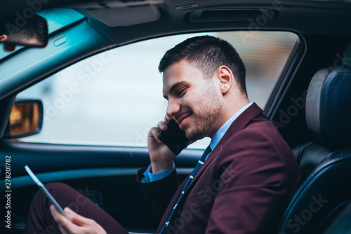 A manager sitting at the front seat of his limo talking on his cellphone while making a lot of hand gestures. © qunica.com