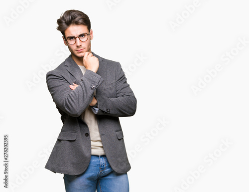 Young business man wearing glasses over isolated background with hand on chin thinking about question, pensive expression. Smiling with thoughtful face. Doubt concept.