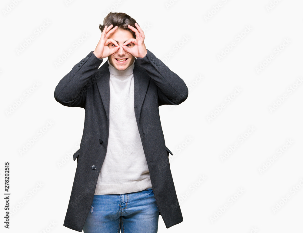 Young elegant man wearing winter coat over isolated background doing ok gesture like binoculars sticking tongue out, eyes looking through fingers. Crazy expression. Young elegant man wearing winter coat over isolated background doing ok gesture like binoculars sticking tongue out, eyes looking through fingers. Crazy expression.