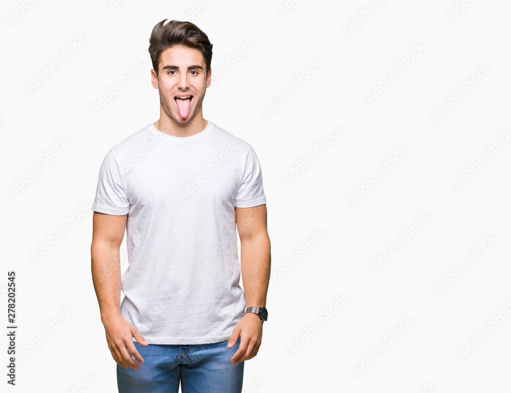 Obraz premium Young handsome man wearing white t-shirt over isolated background sticking tongue out happy with funny expression. Emotion concept.