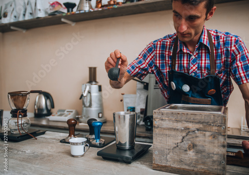 Smiling male barista is preparing espresso at coffee shop