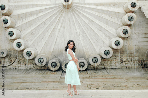 young woman in white dress outside posing and smiling