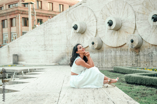 young woman in white dress outside posing and smiling