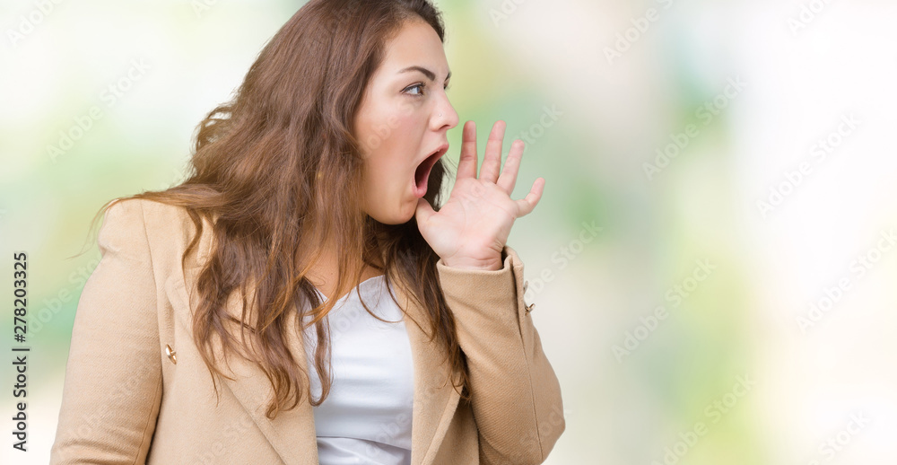 Beautiful plus size young woman wearing winter coat over isolated background shouting and screaming loud to side with hand on mouth. Communication concept. Beautiful plus size young woman wearing winter coat over isolated background shouting and screaming loud to side with hand on mouth. Communication concept.