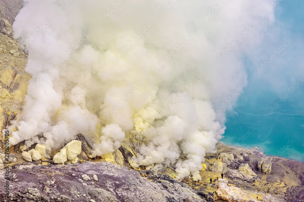 Crater of a volcano with a green sulfuric volcanic lake and volcanic smoke. View of the smoking volcano Kawah Ijen in Indonesia