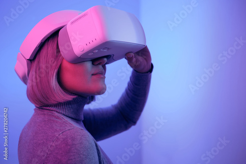 Woman using VR goggles standing in neon light. 360 degrees. Virtual reality headset. Wearing virtual reality goggles. Smartphone with VR. Virtual reality video