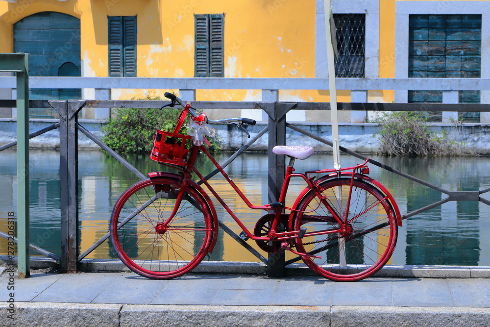 bicicletta rossa con case colorate e fiume a gaggiano in italia, red bicycle with colorful houses and river in gaggiano village in Italy