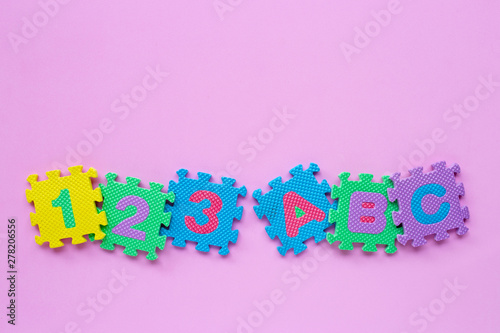 Alphabet puzzle with number puzzle on pink background.