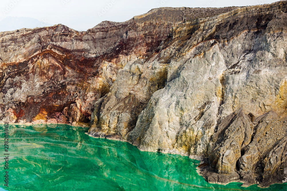 Shot of the shore of a green sulfur lake in the crater of the Kawah Ijen volcano in Indonesia. Mountain landscape