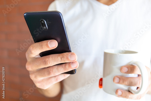 smartphone and a cup of coffee in the guy's hand